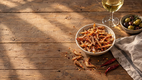 Gegrillte Shrimps als Apéro-Snack in einer Schale auf einem Holztisch, daneben Oliven und Weisswein