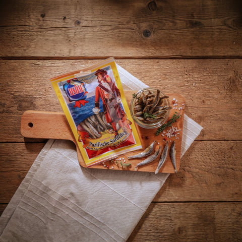 Pazifische Sardelle – Packung und Snack auf dem Holztisch