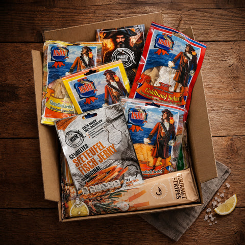 Probierpaket Snack Mix – gefüllter Karton mit Fischsnacks auf dem Holztisch